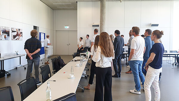 Participants of the GoProZero consortium meeting stand in a conference room and look at a presentation wall together.