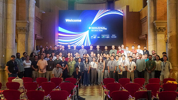 Gruppenfoto der Teilnehmenden der ELLIS Summer School on Autonomous Driving in einem Veranstaltungsraum in Barcelona.