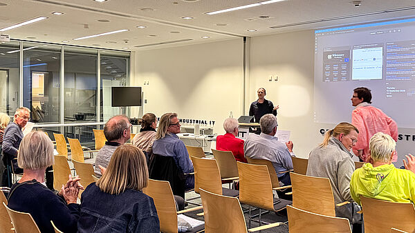 Auf einer großen Leinwand ist die Faktencheck-Plattform Mimikama zu sehen; davor sitzen Teilnehmende des Workshops.