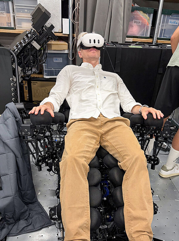 Carsten Röcker sitzt auf einem Prototyp eines haptischen AR-Stuhls an der Keio University in Tokio.