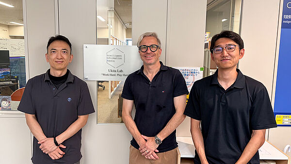 Carsten Röcker steht gemeinsam mit Professor Norimichi Ukita und Shozaburo Hirano am Toyota Technological Institute in Nagoya.