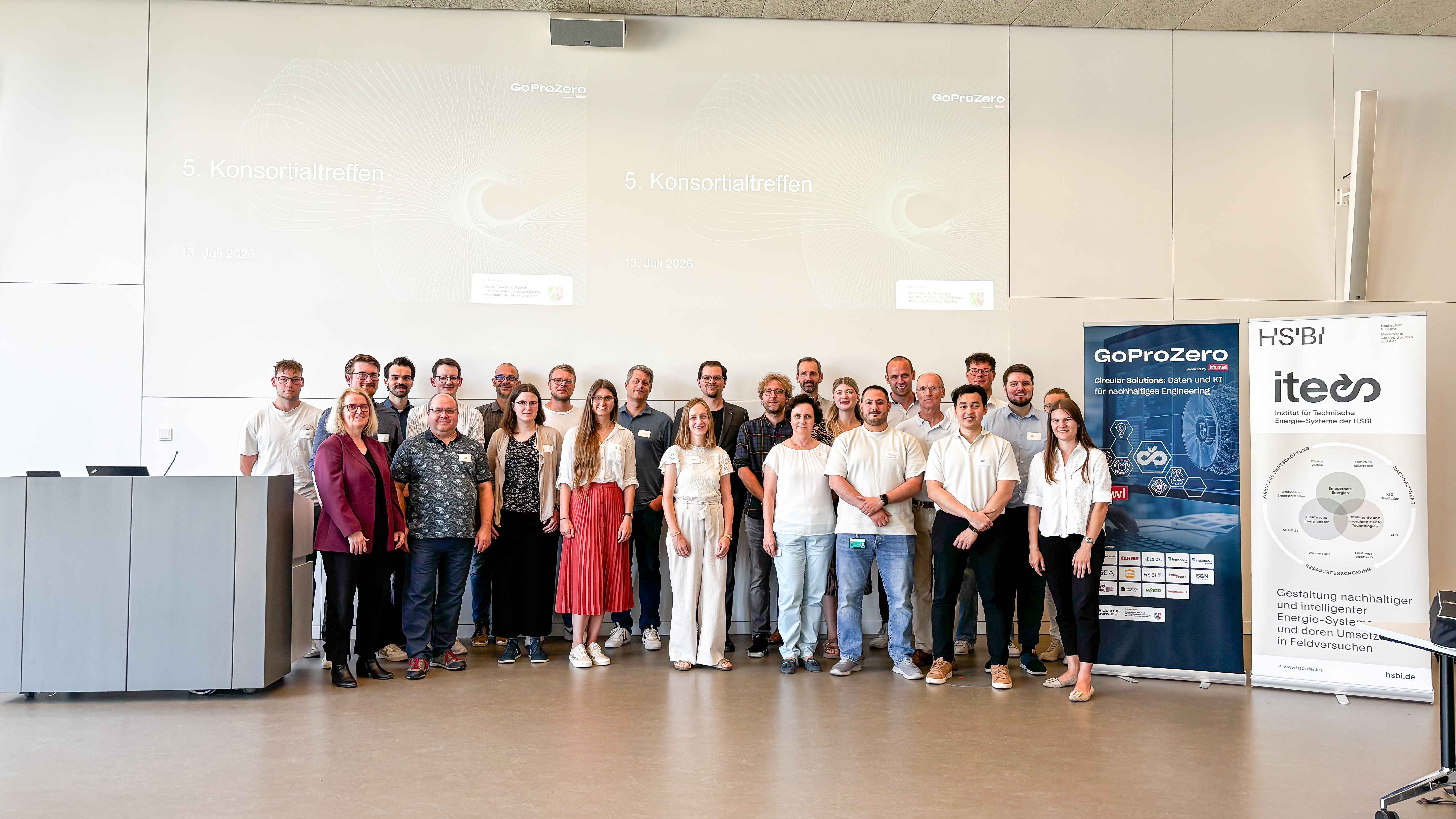 Gruppenfoto der Teilnehmenden des fünften GoProZero-Konsortialtreffens vor Präsentationsfläche und Projektbannern an der Hochschule Bielefeld.