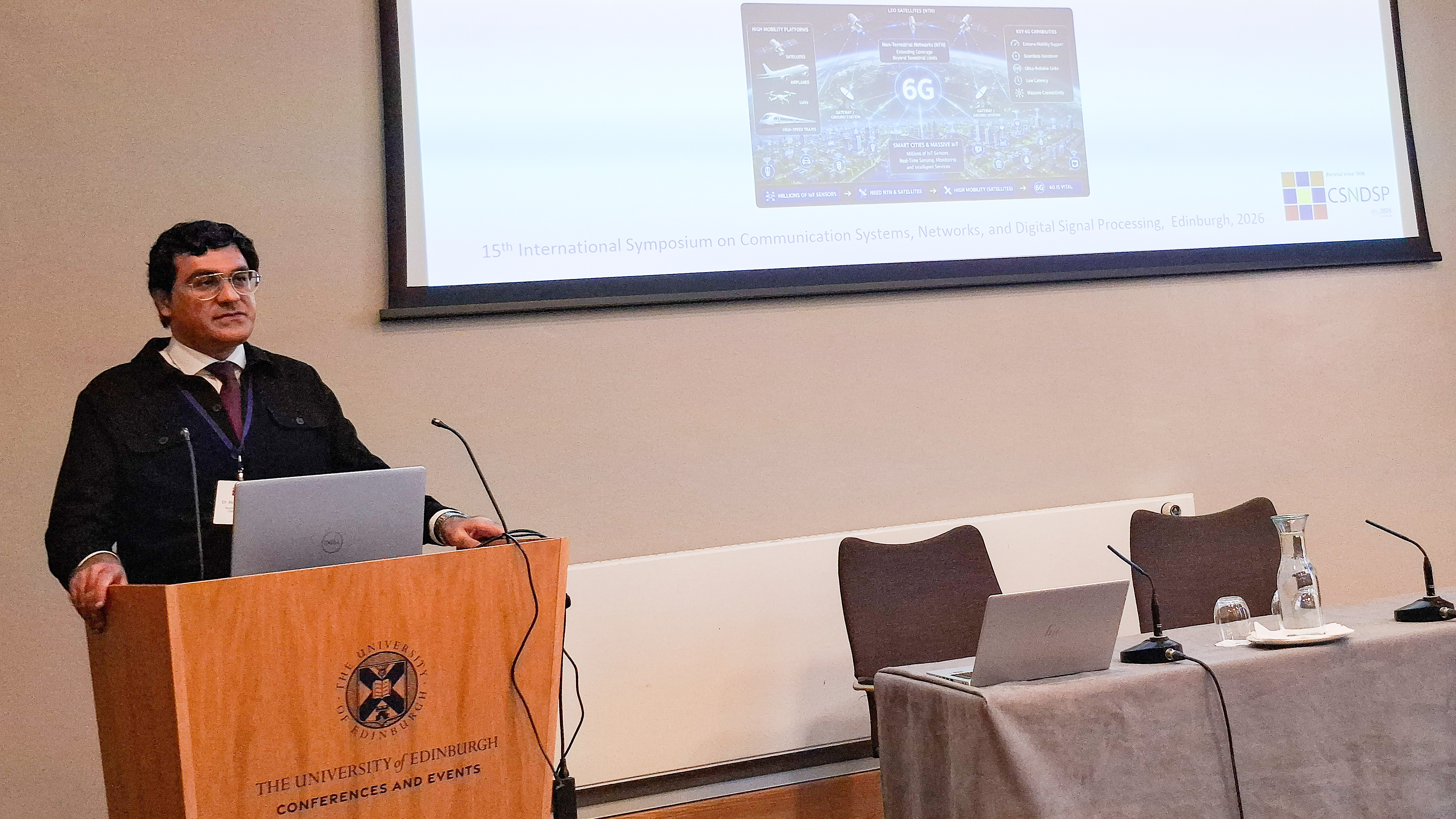 Dr. Mohsen Kazemian steht neben seinem wissenschaftlichen Poster zur Kanalvorhersage in hochmobilen 6G-Netzwerken auf der IEEE-Konferenz CSNDSP 2026.