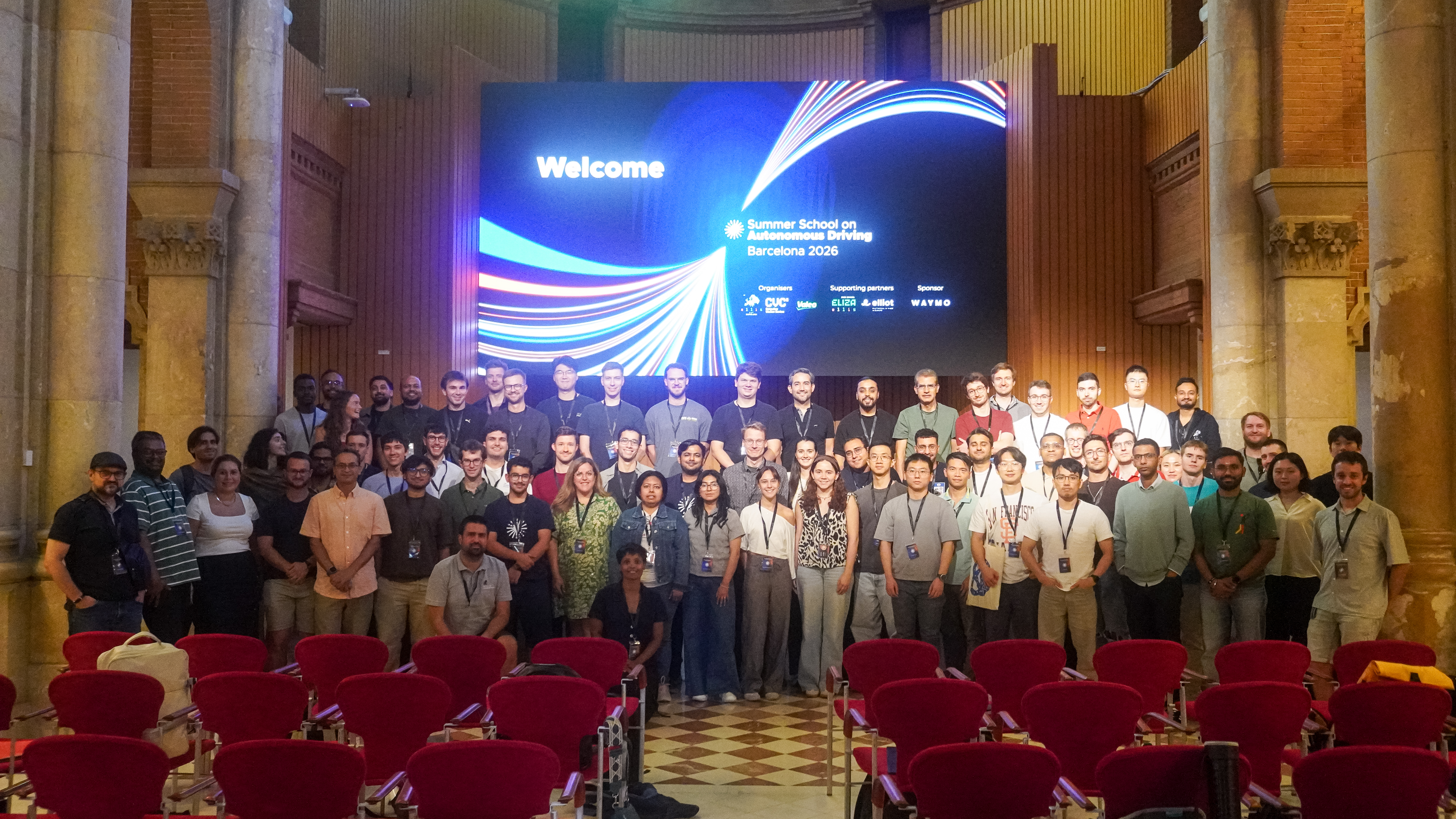 Gruppenfoto der Teilnehmenden der ELLIS Summer School on Autonomous Driving in einem Veranstaltungsraum in Barcelona.
