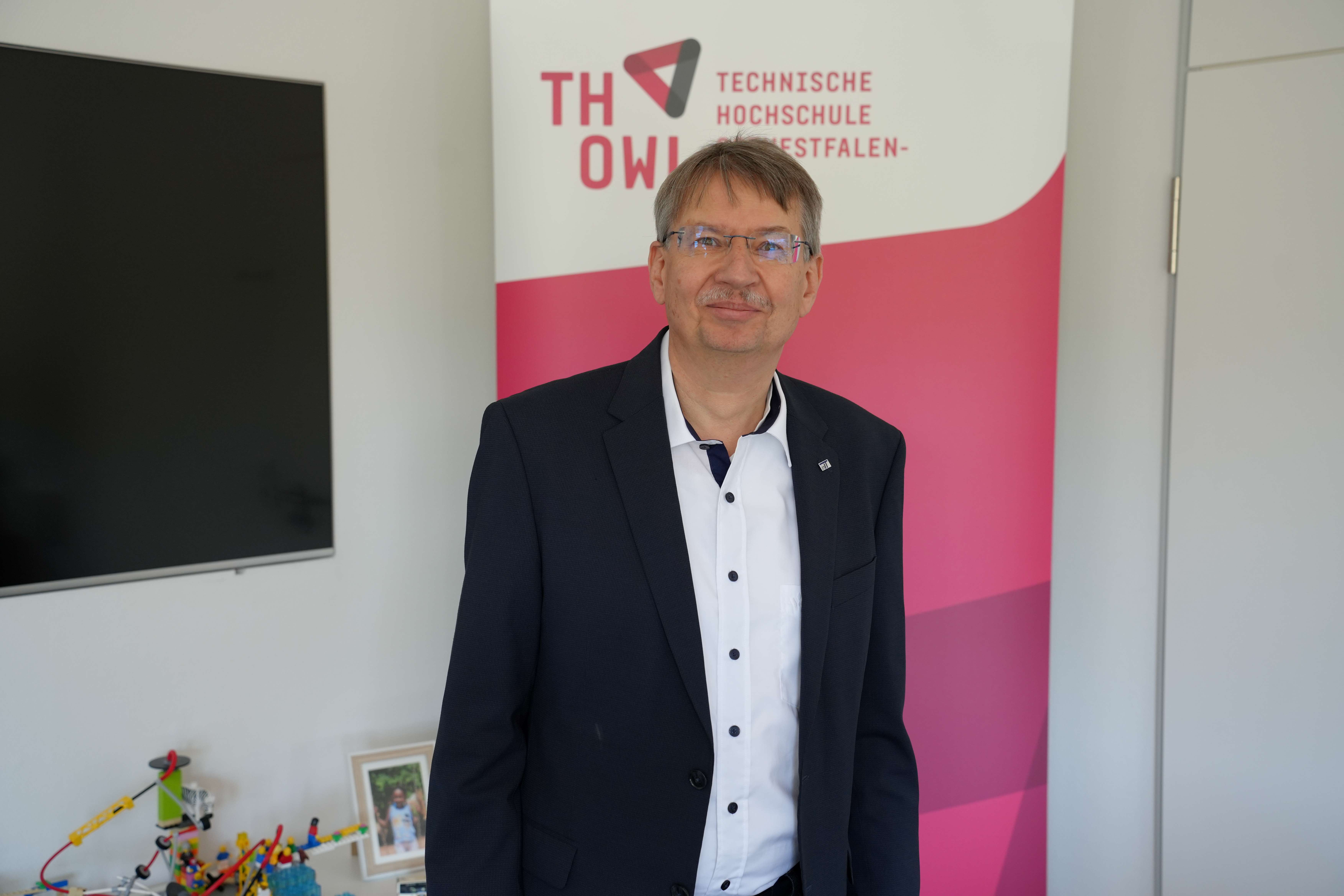 Sen-Prof. Dr. Volker Lohweg steht vor dem Logo der Technischen Hochschule Ostwestfalen-Lippe.
